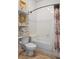Cozy white tiled bathroom showcasing a toilet and bathtub with vintage gold framed art and stacked towels on shelves at 15053 Peace Blvd, Spring Hill, FL 34610
