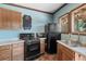 Compact kitchen with wooden cabinetry, black appliances, and ample counter space, creating a functional cooking area at 15053 Peace Blvd, Spring Hill, FL 34610
