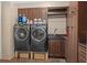 Modern laundry room featuring dark wood cabinets, a sink, and front loading washer and dryer at 15053 Peace Blvd, Spring Hill, FL 34610