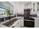 Modern kitchen with white cabinets, stainless steel appliances, and black and white backsplash at 19 N Pine Cir, Belleair, FL 33756