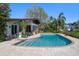 Gorgeous in-ground pool with brick surround, adjacent to the home with a covered patio, perfect for relaxation at 19 N Pine Cir, Belleair, FL 33756