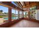 Inviting sun room with wood paneled walls, multiple windows, and a tranquil view of the pool and waterfront at 19 N Pine Cir, Belleair, FL 33756
