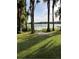 Lush backyard view with mature trees lining a tranquil lake on a sunny day at 22129 Carson Dr, Land O Lakes, FL 34639