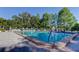 Community pool featuring clear blue water surrounded by brick pavers, lounge chairs, and mature trees at 2557 Laurelwood Dr # 10E, Clearwater, FL 33763