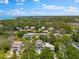 An aerial view of the property nestled within lush trees with a tranquil pond nearby and the bay just beyond at 322 Ontario Ave, Crystal Beach, FL 34681