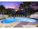 A beautiful backyard pool and spa, lit up at twilight and surrounded by lush tropical landscaping at 322 Ontario Ave, Crystal Beach, FL 34681