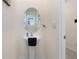 Bathroom featuring a pedestal sink, round mirror, and white fixtures at 32978 Tulip Petal Ln, Wesley Chapel, FL 33545