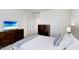 Bedroom with a white comforter, wood dresser, and mounted TV at 32978 Tulip Petal Ln, Wesley Chapel, FL 33545