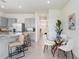 Open kitchen layout with granite island seating, dining table, and view down the hallway at 32978 Tulip Petal Ln, Wesley Chapel, FL 33545