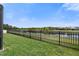 Spacious lawn with black metal fence, offering serene views of a tranquil pond at 4108 Mellon Dr, Odessa, FL 33556
