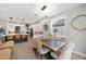 Open-concept dining area featuring a rustic table, upholstered chairs, modern lighting, and views of the kitchen at 4108 Mellon Dr, Odessa, FL 33556