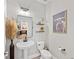 Elegant powder room with a pedestal sink, stylish mirror, and decorative wall art at 4108 Mellon Dr, Odessa, FL 33556