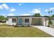 Charming single-story home featuring a covered carport, fresh landscaping, and a vibrant blue front door at 4675 26Th N Ave, St Petersburg, FL 33713