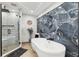 Elegant bathroom with a soaking tub, glass shower, and dramatic stone accent wall at 506 Spring Tree Ct, Tarpon Springs, FL 34689