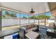 Relax in this screened lanai featuring a ceiling fan, comfortable seating, and views of the backyard at 506 Spring Tree Ct, Tarpon Springs, FL 34689