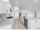 Open kitchen featuring white cabinets, a spacious island, and modern stainless steel appliances at 5958 Talon Preserve Dr, Nokomis, FL 34275