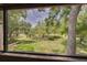 Expansive backyard featuring lush greenery and mature trees, viewed from screened enclosure at 60 Woodridge Cir, Oldsmar, FL 34677