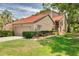 Inviting two-story home with a well-manicured lawn and lush landscaping, including mature trees at 60 Woodridge Cir, Oldsmar, FL 34677