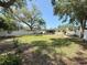 Large backyard featuring a white fence, lush lawn, and mature shade trees at 809 Scotland St, Dunedin, FL 34698