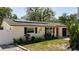 Charming home featuring solar panels, a bright red door, and lush landscaping at 809 Scotland St, Dunedin, FL 34698