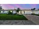 Charming home with a brick driveway, green lawn, and lush tropical landscaping under a twilight sky at 10036 40Th N St # 3, Pinellas Park, FL 33782