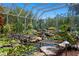Lush backyard pond and gardens encased with a screened in enclosure, with a tennis court beyond the greenery at 147 & 139 Edgewater Dr, Dunedin, FL 34698