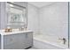 Modern bathroom featuring a soaking tub, walk-in shower, marble countertops, and gray cabinets at 147 & 139 Edgewater Dr, Dunedin, FL 34698