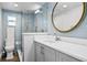 This bathroom offers a modern sink vanity and large round mirror, complemented by blue tiled walls and a shower at 147 & 139 Edgewater Dr, Dunedin, FL 34698