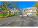 Elegant two-story home with a light gray facade, pristine white trim, and a circular driveway with tropical landscaping at 147 & 139 Edgewater Dr, Dunedin, FL 34698