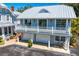 Beautiful grey home featuring white trim, multiple levels with garages, a metal roof, a bicycle, and lush landscaping at 147 & 139 Edgewater Dr, Dunedin, FL 34698