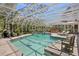 Large enclosed pool with a view of the lush backyard and waterfall feature, lounge chairs, and outdoor dining at 147 & 139 Edgewater Dr, Dunedin, FL 34698