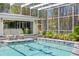 Screened pool with mosaic fish tiles and chairs sits next to lush landscaping and sliding glass doors at 147 & 139 Edgewater Dr, Dunedin, FL 34698