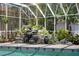 Detailed view of the enclosed pool's rock waterfall feature, complete with decorative pots and lush greenery at 147 & 139 Edgewater Dr, Dunedin, FL 34698