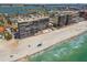 Stunning aerial view of beachfront condos on a white sand beach with clear turquoise water and blue skies at 15462 Gulf Blvd # 504, Madeira Beach, FL 33708