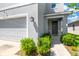 Close up of home's front entry with a gray door, dark wall lanterns and landscaping at 16149 Tuscany Hillside Rd, Odessa, FL 33556