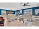 Bright living room with blue accent wall, tile floors, ceiling fan, and comfortable beige couches at 16149 Tuscany Hillside Rd, Odessa, FL 33556