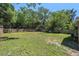 Spacious fenced backyard with green lawn, mature trees, and ample space for outdoor activities at 186 Grand Ave, Brooksville, FL 34604