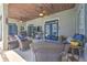 A cozy covered patio with wicker furniture, ceiling fans, wood plank ceiling, and stylish blue doors to the home at 2113 Golf Manor Blvd, Valrico, FL 33596