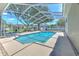 A beautiful screened-in pool featuring a covered deck with lush green trees in the background at 2113 Golf Manor Blvd, Valrico, FL 33596