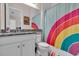 Colorful bathroom featuring rainbow shower curtain and black granite countertop with white cabinetry at 2165 Hollow Forest Ct, Wesley Chapel, FL 33543