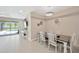 Bright dining area with a rustic table, white chairs, and contemporary lighting, adjacent to the living space and pool view at 2511 Early Dawn Ct, Valrico, FL 33594
