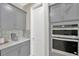This kitchen boasts gray cabinets, stainless steel double ovens, and a tiled backsplash, offering style and functionality at 2511 Early Dawn Ct, Valrico, FL 33594