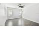 This bedroom has sleek gray wood floors, three bright windows, and a modern ceiling fan at 2650 Countryside Blvd # C203, Clearwater, FL 33761