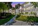 Multi-story condo with a sidewalk and tropical landscaping, including palm trees, bushes, and well-maintained grass at 2650 Countryside Blvd # C203, Clearwater, FL 33761