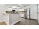 Open kitchen with granite countertops, stainless steel refrigerator, white cabinets, and hardwood-style floors at 2650 Countryside Blvd # C203, Clearwater, FL 33761