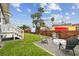 Private backyard oasis featuring a lush lawn, a modern fire pit, and mature palm trees providing shade at 2704 W Main St, Tampa, FL 33607