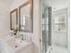 Bright bathroom featuring a double vanity, framed mirrors, a glass-enclosed shower, and ample natural light at 2704 W Main St, Tampa, FL 33607