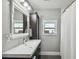 Well-lit bathroom featuring gray walls, a large mirror, and a shower with a white curtain at 2704 W Main St, Tampa, FL 33607