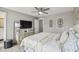 Bedroom featuring a decorative wall, tufted headboard bed, bedside tables, a ceiling fan, and a large television at 2704 W Main St, Tampa, FL 33607