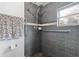 Accessible shower stall with gray tile surround, safety bars, handheld shower head, and mosaic tile floor at 2909 60Th N Ave, St Petersburg, FL 33714